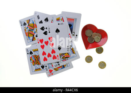 Pile de cartes à jouer traditionnelles sur fond blanc avec Ace of Hearts breloque en forme de bol sur le côté avec le changement lâche dans et à côté. Banque D'Images