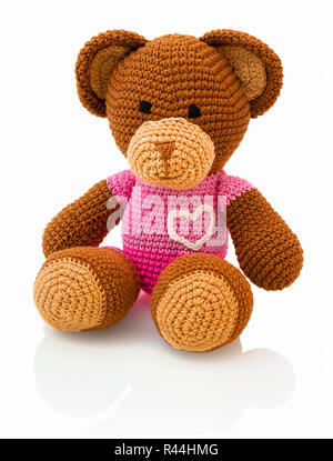 Crochet fait main Cute Bear doll isolé sur fond blanc avec ombre de réflexion. Crochet ludique pinky brown bear assis sur sous-couche blanche. Knitt Banque D'Images