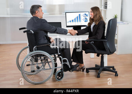 Businesswoman Shaking Hands With Disabled Businessman Banque D'Images