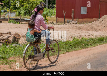 Woman and boy on bicycle in campagne cambodgienne en parc archéologique d'Angkor, près de Siem Reap, Cambodge Banque D'Images