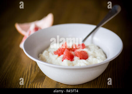 Bouillie bouillie sucrée de semoule dans une assiette avec des tranches de pamplemousse rouge Banque D'Images