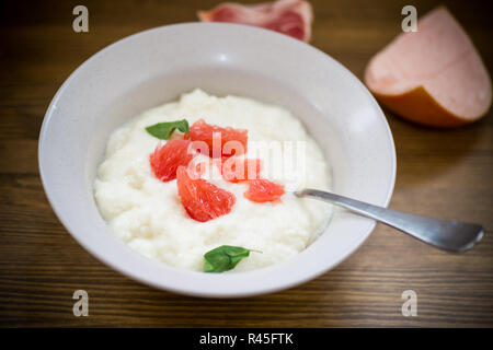 Bouillie bouillie sucrée de semoule dans une assiette avec des tranches de pamplemousse rouge Banque D'Images