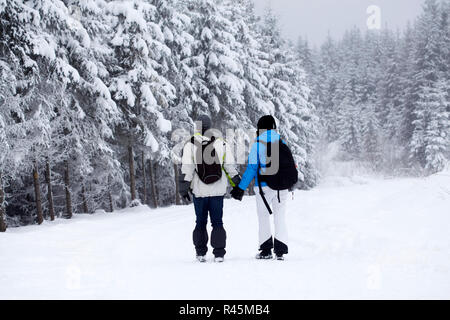 Couple en train de marcher sur le chemin couvert de neige Banque D'Images