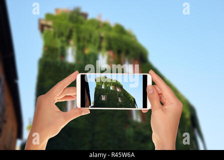 Un touriste prend une photo de l'immeuble est complètement envahi de vigne à la légère dans quartier de Trastevere, Rome, Italie sur un téléphone mobile Banque D'Images