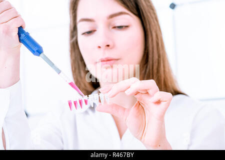 Jeune femme remplir microtubes PCR avec distributeur Banque D'Images