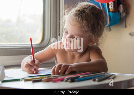 Emporté par la jeune fille attire l'crayon à la table dans un train Banque D'Images