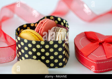 Macarons français sont dans une boîte cadeau en forme de coeur sur fond gris Banque D'Images