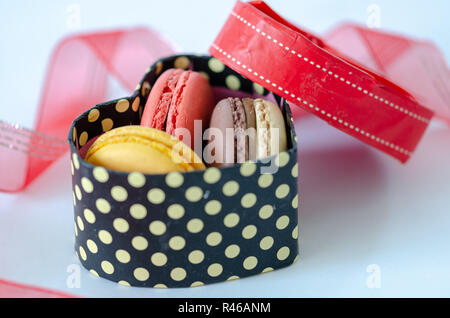 Macarons français sont dans une boîte cadeau en forme de coeur sur fond gris Banque D'Images