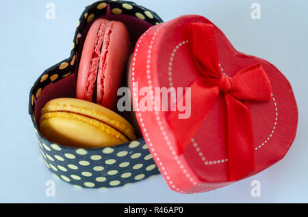 Macarons français sont dans une boîte cadeau en forme de coeur sur fond gris Banque D'Images