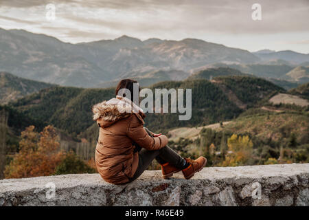 Woman traveler ressemble au bord de la falaise de la montagne en arrière-plan. Banque D'Images