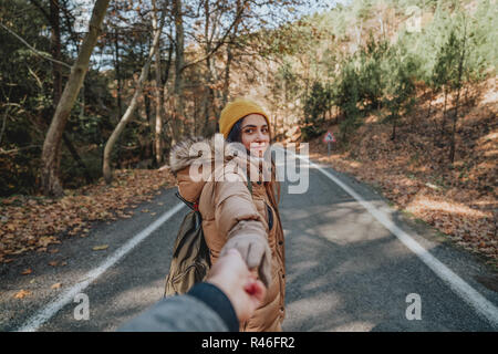 Jeune femme tenant la main de l'homme et le conduisant sur nature plein air. Couple in love Banque D'Images