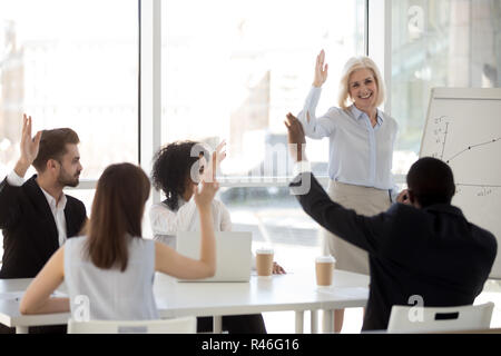 Coach Smiling raising hand avec équipe diversifiée s'engager dans le vote Banque D'Images