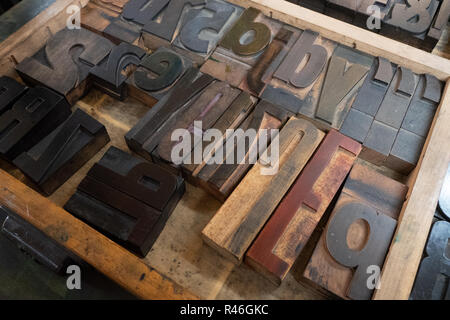 Un ensemble de grandes sans serif lettres en métal et en bois posé sur un plateau prêt à être utilisé dans une ancienne presse à imprimer Heidelberg. Banque D'Images