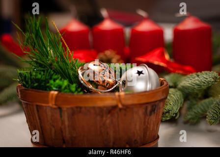 Une petite boîte en bois avec des branches et des cloches de Noël en face d'une couronne de l'avent Banque D'Images