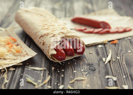 Saucisses épicées dans le pain pita sur une table en bois Banque D'Images