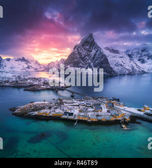 Vue aérienne de Hamnoy au coucher du soleil spectaculaire en hiver dans les îles Lofoten, Norvège. Moody paysage avec bleu de la mer, montagnes enneigées, rochers, village, construire Banque D'Images