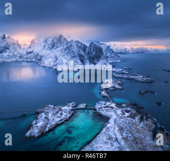 Vue aérienne de Hamnoy au coucher du soleil spectaculaire en hiver dans les îles Lofoten, Norvège. Moody paysage avec bleu de la mer, montagnes enneigées, rochers, village, construire Banque D'Images