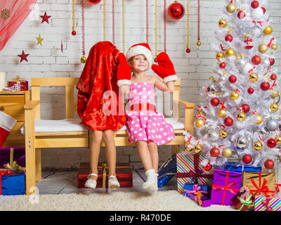 Sur le banc se trouve une jeune fille dans un chapeau et des mitaines de Santa Claus, l'autre fille portait un sac sur sa tête Banque D'Images