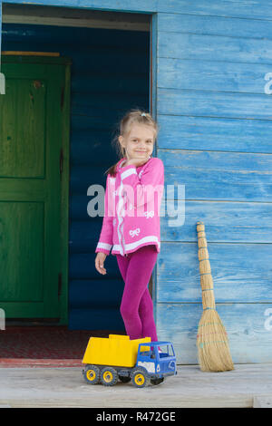 Happy girl jouant avec la machine sur le porche d'une maison en bois Banque D'Images