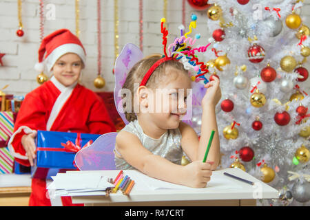 La jeune fille ramassa un artifice de jouets sur la tête, le Père Noël assis derrière son Banque D'Images