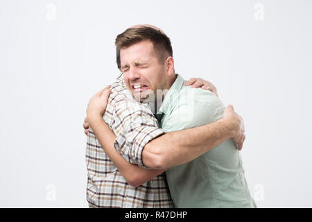 Fils mature est en train de pleurer sur l'épaule de son père et se sentir contrarié cause de son erreur. Banque D'Images