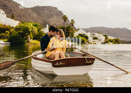 Jeune couple appréciant leur bateau date dans un lac. Couple amoureux assis ensemble dans un bateau de toucher leurs têtes à la recherche à l'autre. Banque D'Images