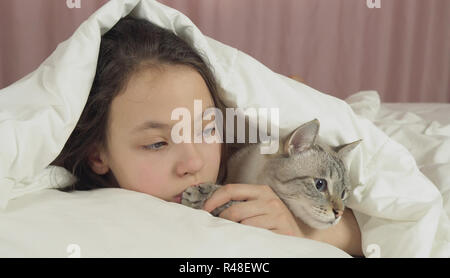 Happy teen girl baisers et des pourparlers avec Thai cat in bed Banque D'Images