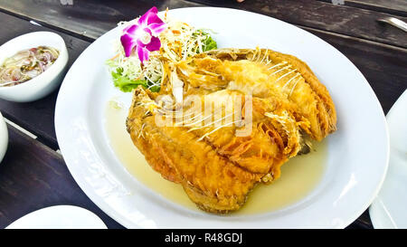 Le poisson frit avec sauce aux fruits de mer épicé thaï aigre et piquante et sauce Thaï (). Banque D'Images