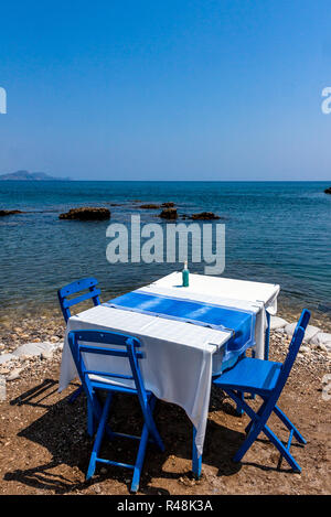 Les tables avec chaises en taverne grecque traditionnelle dans la région de Kolympia ville sur la côte de l'île de Rhodes, Grèce. Banque D'Images