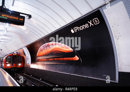 Train de tube en passant une petite annonce affiche pour nouveau Apple iPhone XS, affiche publicitaire dans le métro de Londres, la voie Banque D'Images