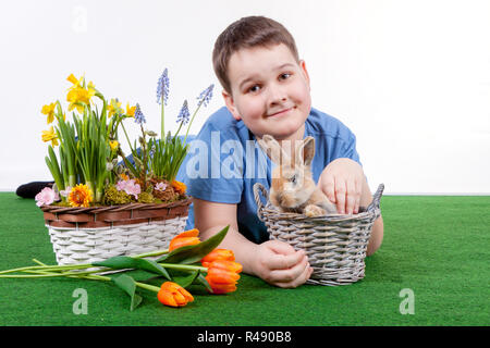 Jeune garçon avec des fleurs de printemps et de lapin sur fond blanc. Banque D'Images