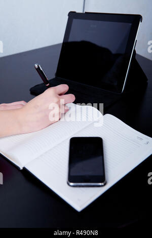 Femme d'affaires dans un café prendre des notes dans un journal, sur l'arrière-plan du téléphone et tablette Banque D'Images