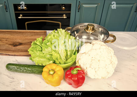 Casserole et le chou-fleur, poivrons, concombre, salade verte feuilles sur une table de cuisine. Végétarien, légumes, santé, nutrition concept Food cooking culinary cu Banque D'Images