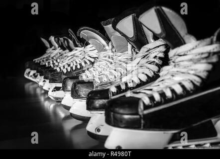 Paires de patins de hockey sur glace alignées dans une sombre salle de casier Banque D'Images