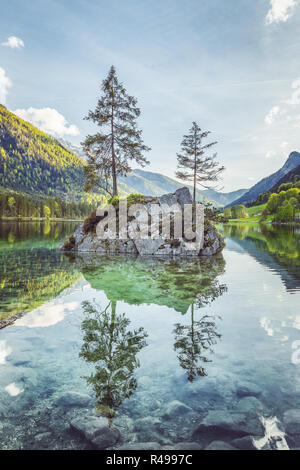 Belle scène d'arbres sur une île de roche dans un paysage idyllique au charmant lac Hintersee avec ciel bleu et nuages dans l'été, parc national de Berchtesgaden Banque D'Images