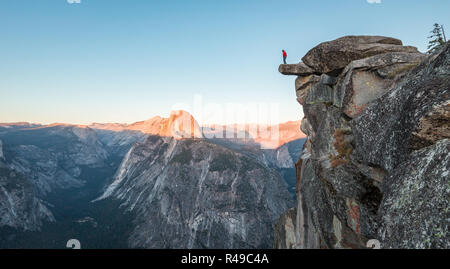 L'intrépide randonneur est debout sur un rocher en surplomb en profitant de la vue vers célèbre Demi Dôme à Glacier Point oublier dans beau crépuscule du soir Banque D'Images