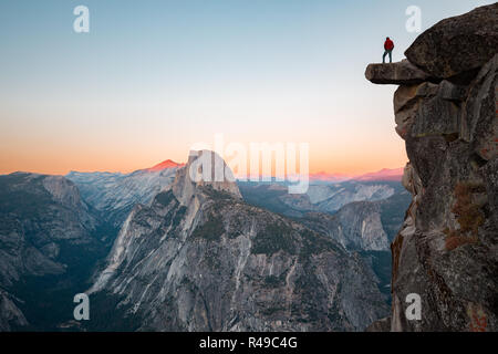 L'intrépide randonneur est debout sur un rocher en surplomb en profitant de la vue vers célèbre Demi Dôme à Glacier Point oublier dans beau crépuscule du soir Banque D'Images