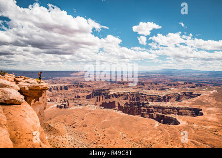 Un male hiker est debout sur le bord d'une falaise spectaculaire bénéficiant d'un paysage pittoresque de négliger dans le magnifique Parc National de Canyonlands, Utah, USA Banque D'Images