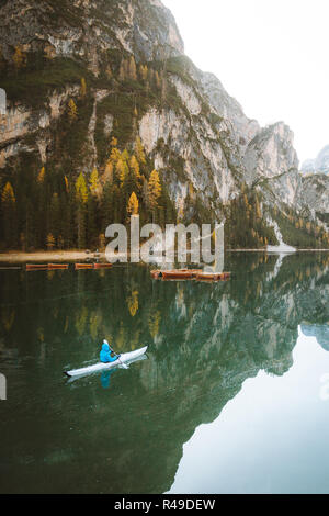 Belle vue sur célèbre Lago di Braies avec jeune homme en kayak au lever du soleil à l'automne, Dolomites, Italie Banque D'Images