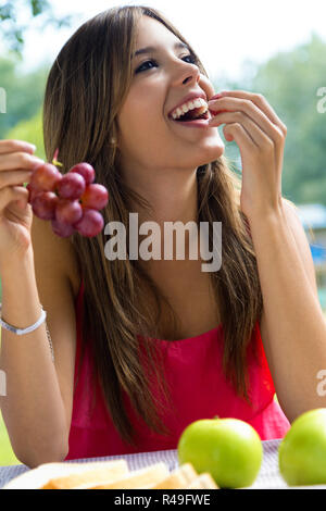 Young Girl eating grapes on pique-nique romantique dans la campagne. Banque D'Images