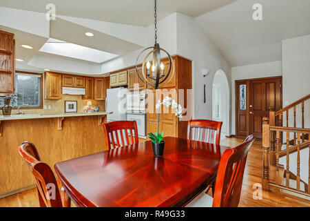 Chambre Cuisine intérieur en bois de cerisier américain chambre avec table à manger et des armoires orangées en grand prix. Banque D'Images