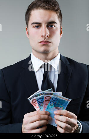 Jeune homme dans la soirée de la détention de monnaie. Banque D'Images