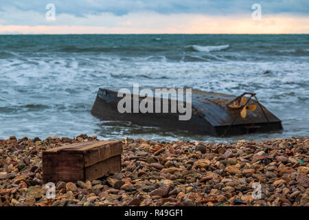 Une boîte de rangement est allongé sur le rivage à côté d'un bateau renversé après un naufrage en raison de typhon Soulik Banque D'Images