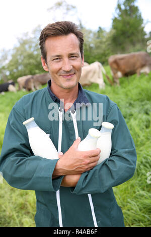 Farmer in field holding bouteilles de lait Banque D'Images