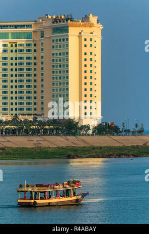 Bateau de croisière au coucher du soleil & Sokha hotel au confluent du Tonlé Sap et les rivières du Mékong ; Central Riverfront, Phnom Penh, Cambodge Banque D'Images