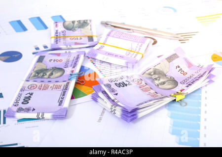 Nouveau pack de Roupie indienne 100 notes avec papier et stylo. Isolé sur fond de bois. Banque D'Images