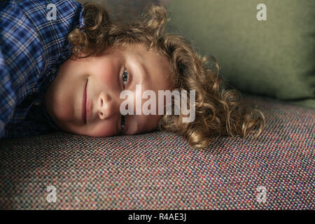 Petit garçon allongé sur le sofa du salon à la maison Banque D'Images
