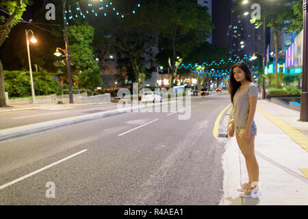 Belle jeune femme asiatique d'errer dans les rues de la ville à nig Banque D'Images