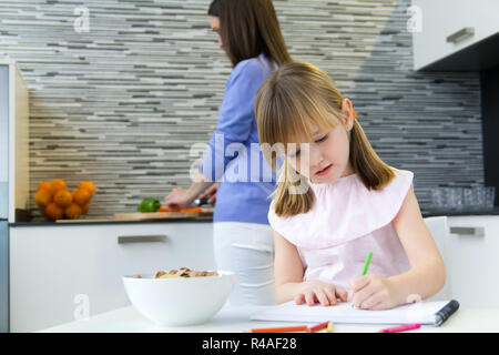 Dessin de l'enfant avec des crayons, assis à table dans la cuisine à la maison Banque D'Images