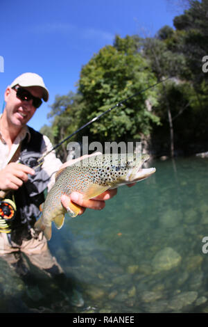 Fly fisherman holding truite fario a rencontré récemment Banque D'Images